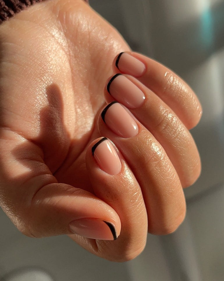 Nude gel nails with black tips by Chelsea Barker