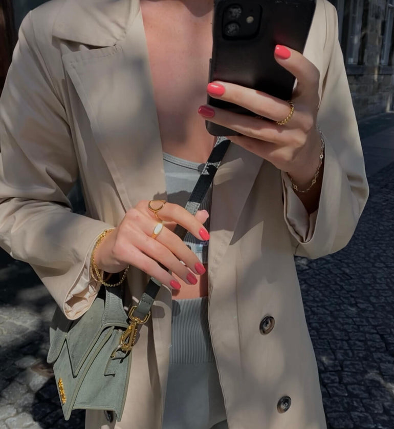 Woman wearing trench coat over gumwear with coral pink gel nails