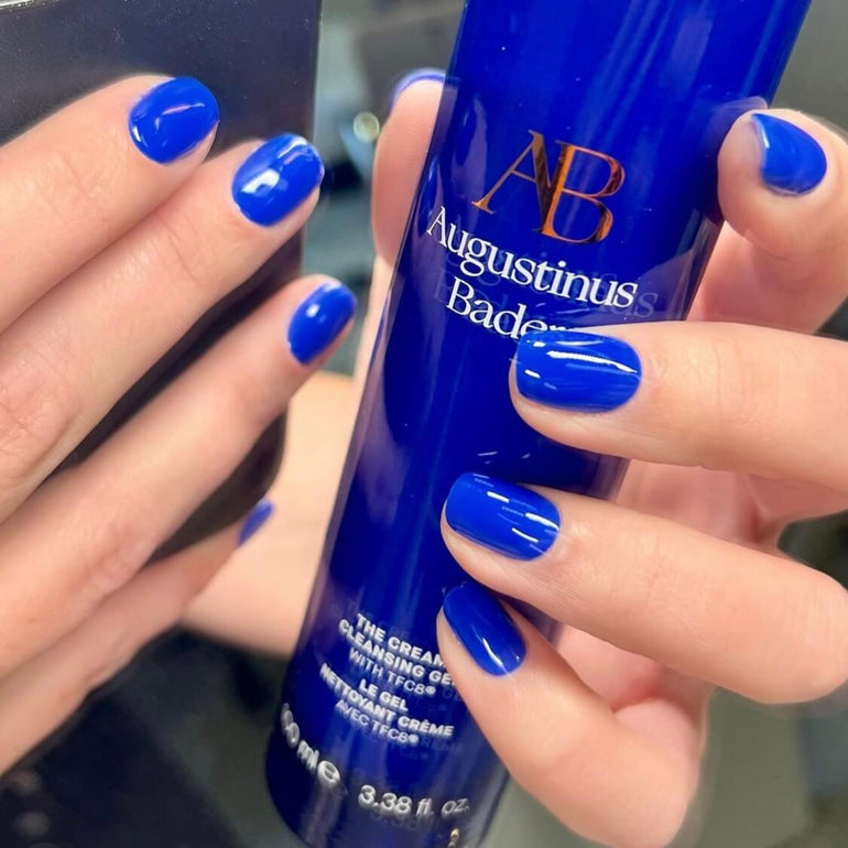 Bright blue gel nails holding Augustinus Bader bottle by Kendal Gazal