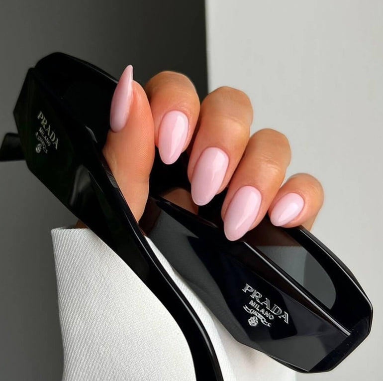 Bright nude gel nails holding Prada sunglasses by Naomi Brown